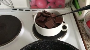 Siyah ve beyaz çikolata ocakta bir kase parçaları. Çikolata bir tatlı yapmak için bir su banyosunda erimiş.