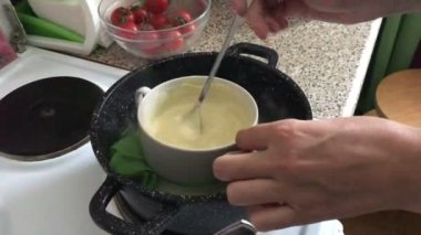 Kadın beyaz çikolata bir plaka üzerinde karıştırma. Çikolata bir tatlı yapmak için bir su banyosunda erimiş.
