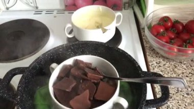 Siyah ve beyaz çikolata ocakta bir kase parçaları. Çikolata bir tatlı yapmak için bir su banyosunda erimiş.