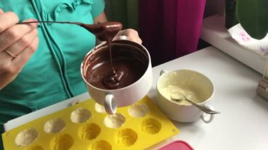 Bir kadın silikon kalıp içinde erimiş bitter çikolata koyar. Formu duvarlarının yağlama için. Tatlı yemek.