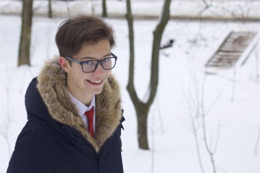 Bir kürk yakalı ceket genç bir adam portresi. Kış parkta bir yürüyüş.