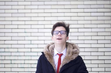 Bir kürk yakalı ceket genç bir adam portresi. Bir tuğla duvar arka plan üzerinde.