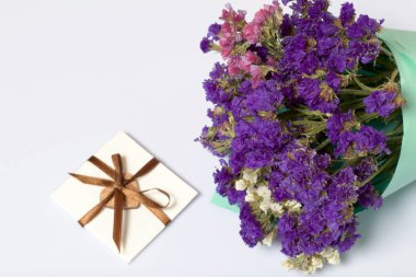 Renkli kağıda sarılmış Kuru çiçekler Buket. Küçük bir tebrik kartı. Beyaz bir arka plan üzerinde.