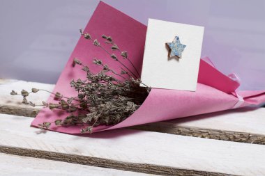 Renkli kağıda sarılmış Kuru çiçekler Buket. Küçük bir tebrik kartı.