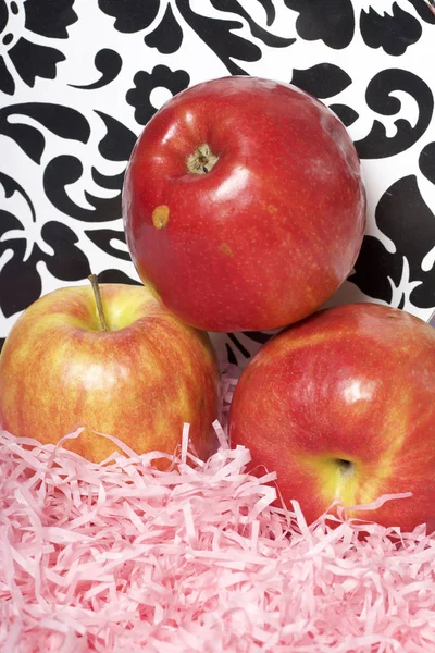 Ripe juicy apples. Lie on paper shavings. On the tracery background.