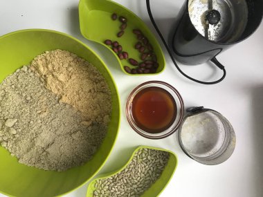 Ev yapımı helva yapmak için malzemeler. Kavrulmuş fıstık ve kaplarda tohumları. Yakınlarda bir kahve değirmeni, bal ve doğranmış malzemeler olduğunu.