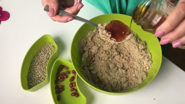 Kvinna Lägger Matsked Honung Behållare Med Krossade Jordnötter Och Solrosfrön — Stockvideo