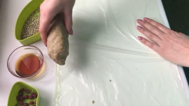 一名妇女用压碎的花生 葵花籽和蜂蜜从混合物中卷起香肠 自制的 Halva — 图库视频影像