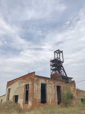 Parkta arasında eski bir bina kalıntıları. Ezilmiş tuğla ve terk edilmiş metal yapılar.