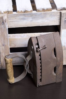 Eski demir, kömürü tarafından ısıtılır. Bir ahşap kutu yanında ayakta.