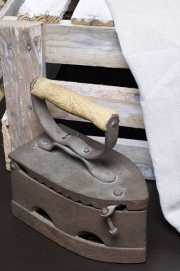 Eski demir, kömürü tarafından ısıtılır. Keten kumaş ve ahşap kutu yanında durduğunu.