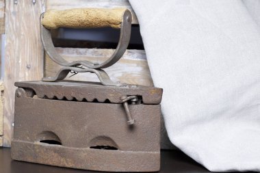 Eski demir, kömürü tarafından ısıtılır. Keten kumaş ve ahşap kutu yanında durduğunu.