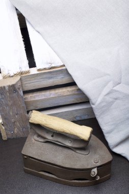 Eski demir, kömürü tarafından ısıtılır. Keten kumaş ve ahşap kutu yanında durduğunu.