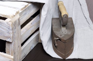 Eski demir, kömürü tarafından ısıtılır. Keten kumaş ve ahşap kutu yanında durduğunu.