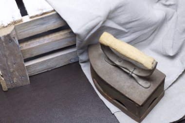 Eski demir, kömürü tarafından ısıtılır. Keten kumaş ve ahşap kutu yanında durduğunu.