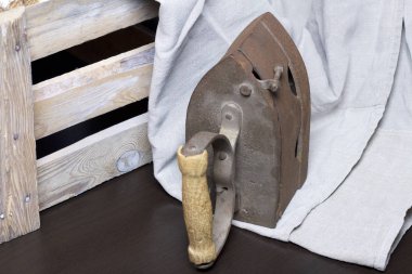 Eski demir, kömürü tarafından ısıtılır. Keten kumaş ve ahşap kutu yanında durduğunu.