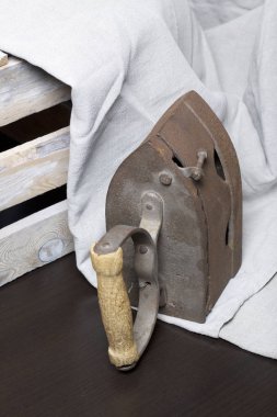 Eski demir, kömürü tarafından ısıtılır. Keten kumaş ve ahşap kutu yanında durduğunu.