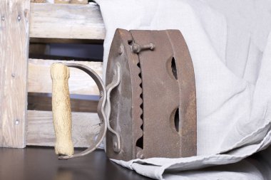 Eski demir, kömürü tarafından ısıtılır. Keten kumaş ve ahşap kutu yanında durduğunu.