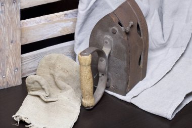 Eski demir, kömürü tarafından ısıtılır. Keten kumaş ve ahşap kutu yanında durduğunu.