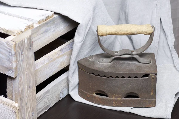 Old iron, heated by hot coals. Standing next to a wooden box and linen cloth.