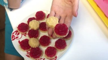 Bir kadın hazır jöle tatlılar elinde tutan ve bir tabağa yerleştirmektedir. İki katlı jöle tatlılar.