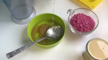 Kadın yem için jelatin ekler ve bir kaşık ile karıştırır. Yakınlarda jöle yapmak için diğer unsurlarıdır şekerler.