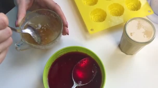 一个女人用勺子把水果明胶混合在一起 附近还有其他制作果冻糖果的原料 — 图库视频影像