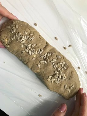 Bir kadın bir karışımı ezilmiş fıstık, ayçekirdeği ve bal ile gelen bir sosis alır. Ev yapımı Helva yemek.