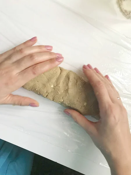 A woman rolls a sausage from a mixture with crushed peanuts, sunflower seeds and honey. Homemade halva cooking.