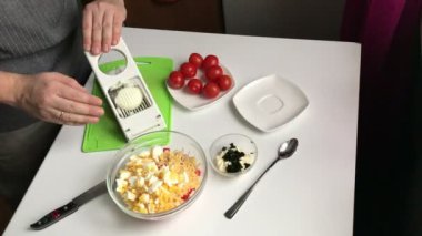 Bir adam bir yumurta kesici ile haşlanmış yumurta pirzola. Sopa, peynir, yumurta ve domates yemek yengeç salata.