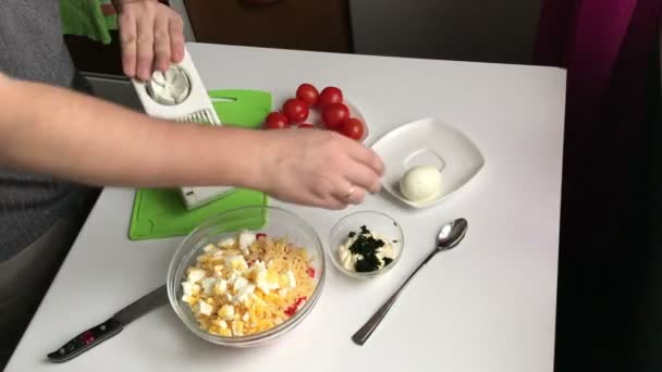一个人用切蛋器切煮鸡蛋 螃蟹棒 鸡蛋和西红柿的烹饪沙拉 — 图库视频影像