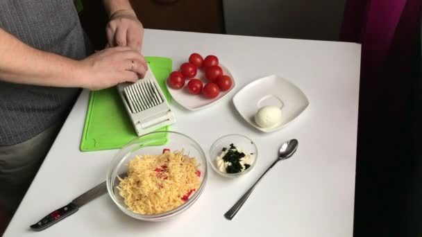 A man chops boiled eggs with an egg cutter. Cooking salad of crab sticks, cheese, eggs and tomatoes. — Stock Footage Man Chops Boiled Eggs Egg Cutter Cooking Salad Crab Sticks Video Clip
