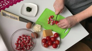 Bir adam yengeç sopa keser. Sopa, peynir, yumurta ve domates yemek yengeç salata.