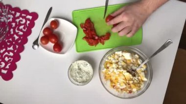 Bir adam bir kesme tahtası üzerinde domates dilimleri. Sopa, peynir, yumurta ve domates yemek yengeç salata. Timelapse
