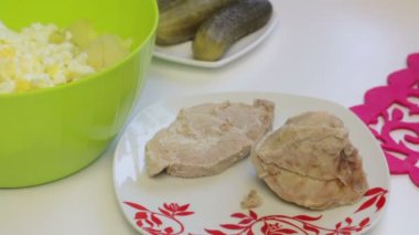 Bir kadın haşlanmış yumurta bir kapta darbeye dökülen. Tablo yüzeyinde salata için malzemeler. Et salatası yumurta, patates, salatalık ve bezelye ile pişirme.