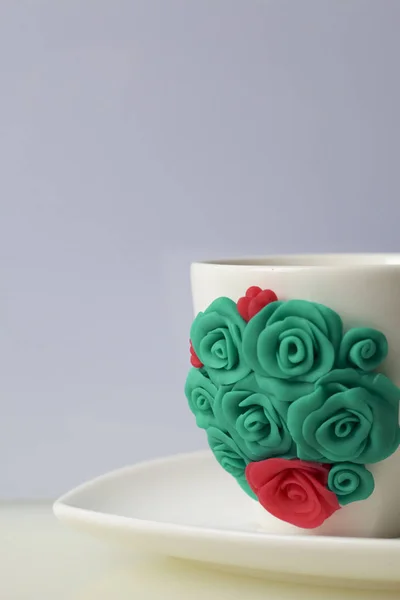 Mug, decorated with flowers made of polymer clay. Crafts from polymer clay. Mug decorated with stucco made of polymer clay