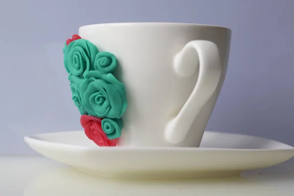 Mug, decorated with flowers made of polymer clay. Crafts from polymer clay. Mug decorated with stucco made of polymer clay