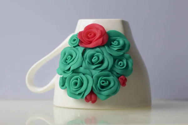 Mug, decorated with flowers made of polymer clay. Crafts from polymer clay. Mug decorated with stucco made of polymer clay