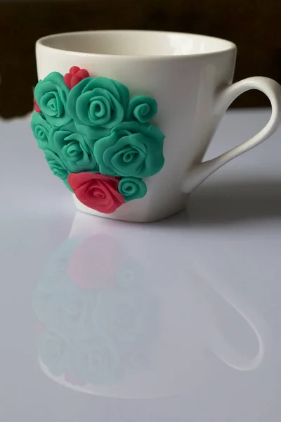 Mug, decorated with flowers made of polymer clay. Crafts from polymer clay. Mug decorated with stucco made of polymer clay