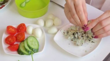 Bir kadın bıldırcın haşlanmış yumurta kabuk temizler. Bir kenara koyarak. Salata hazırlık için.