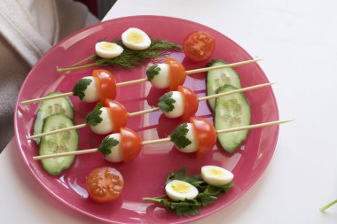 Kebabs from quail eggs and tomatoes strung on wooden skewers in the shape of mushrooms. clipart