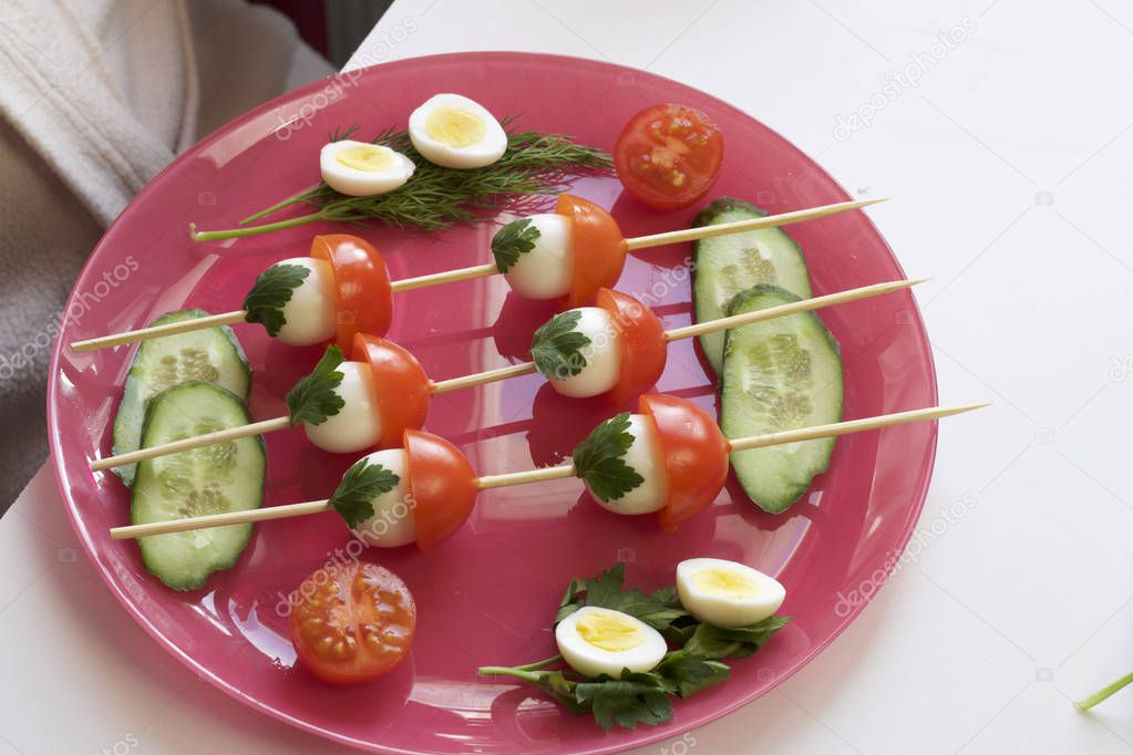 Kebabs from quail eggs and tomatoes strung on wooden skewers in the shape of mushrooms.