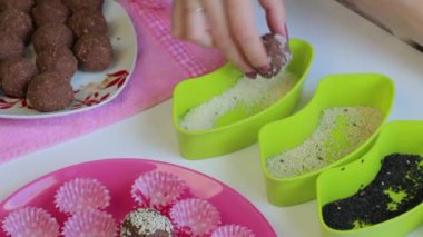 Bir kadın kakao tozu ve eritilmiş tereyağı topları Hindistan cevizi fiş alır. Çevre kapsayıcılar sos ile. Tatlılar yapmak için.