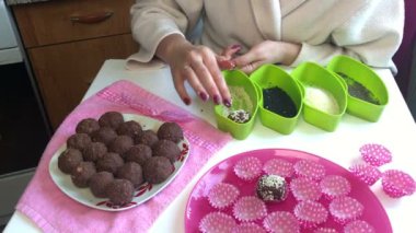 Bir kadın susam içinde kakao tozu ve eritilmiş tereyağı topları alır. O zaman şeklinde yerleştirmektedir. Çevre kapsayıcılar sos ile. Tatlılar yapmak için.