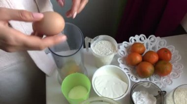 Bisküvi rulo pişirme ricotta ve mandarin ile doldurulmuş. Bir kadın bir blender kaseye tavuk yumurtası bayıltır.