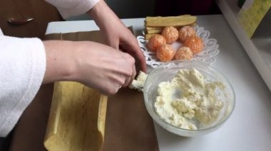 Bisküvi rulo pişirme ricotta ve mandarin ile doldurulmuş. Bir kadın ricotta doldurma bir bisküvi kek üzerine koyar. Dolgu yapmak için tablo yüzeyine yakın unsurlarıdır.