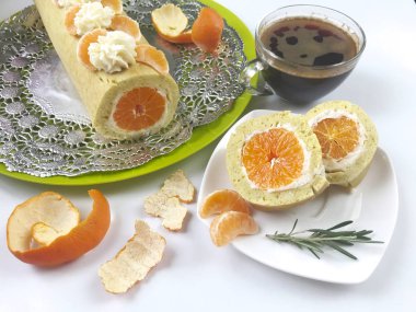 Bisküvi rulo pişirme ricotta ve mandarin ile doldurulmuş. Hazır rulo bir tepside yatıyor. Sonraki tabağı üzerinde rulo kesme parçasıdır.