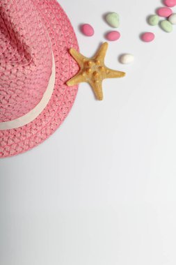 Yaz tatili için aksesuarlar. Beyaz bir arka plan üzerine şapka. Renkli çakıl ve denizyıldızı.