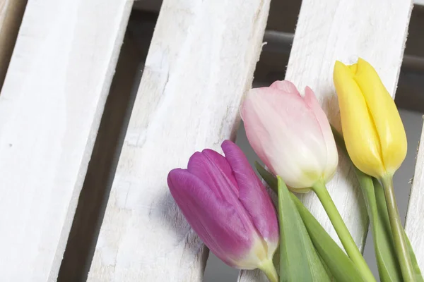 Fiori primaverili. Un bouquet di tulipani di diversi colori sullo sfondo di tavole di legno . — Foto Stock