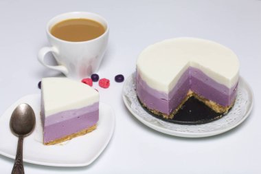 Yaban mersinli cheesecake. Bir uçan daire üzerinde hazır tatlı bir parça. Jöle katmanları farklı renklerde görülebilir.